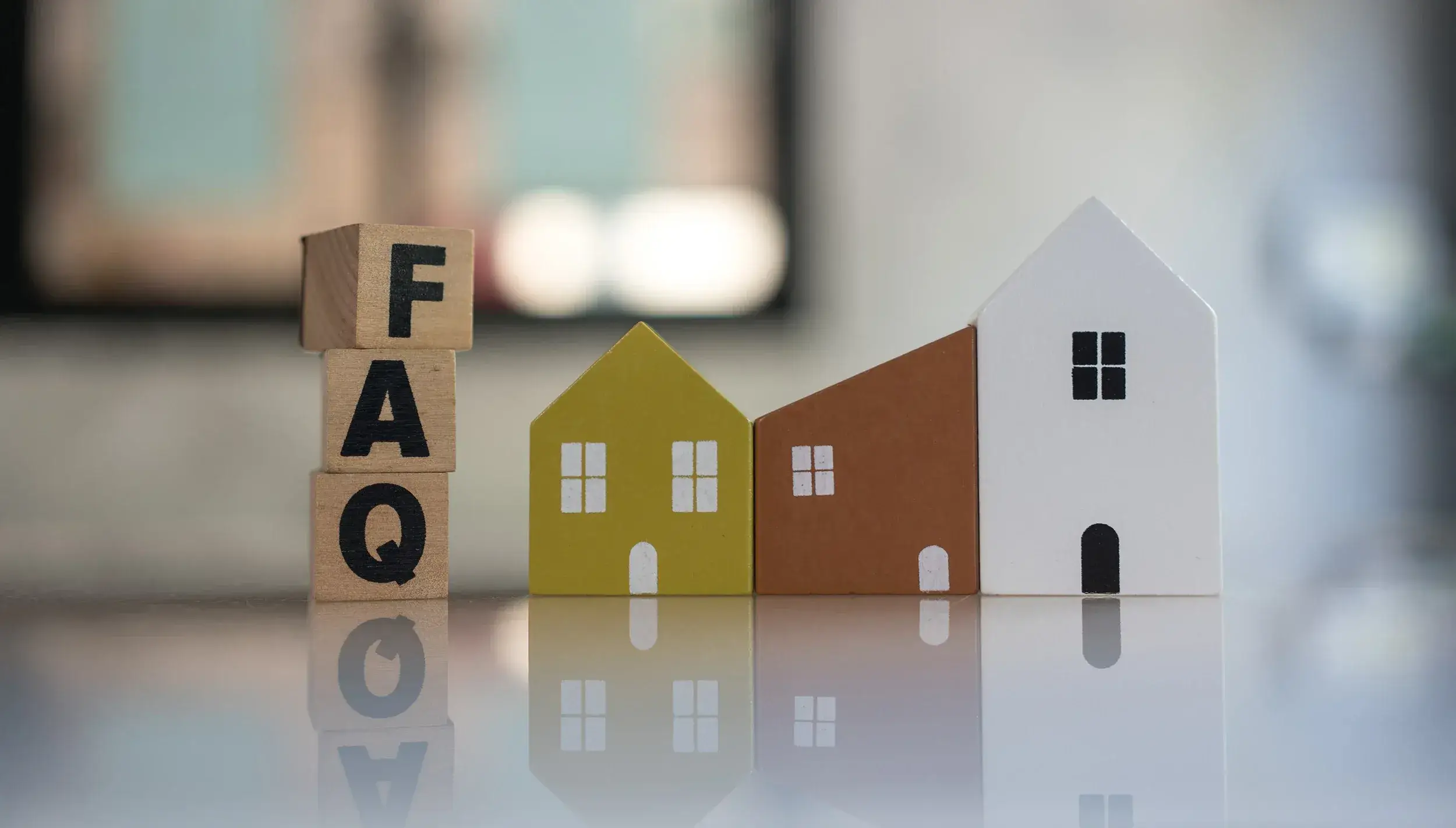 Vanliga frågor och svar om teknisk förvaltning i Stockholm – träklossar med bokstäverna FAQ bredvid miniatyrhus