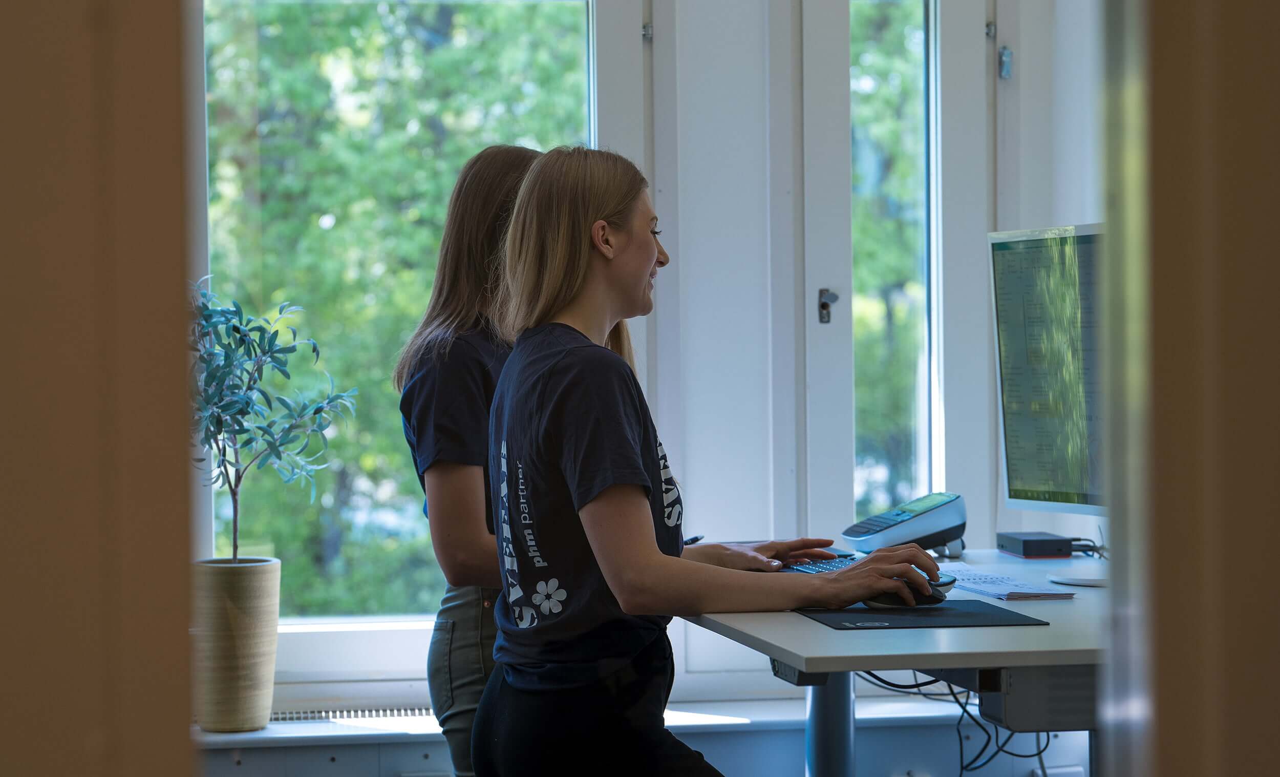 SVEFAB-kundservicemedarbetare i marinblå pikétröja tar emot felanmälan via telefon vid skrivbord med ärendehanteringssystem på skärmen