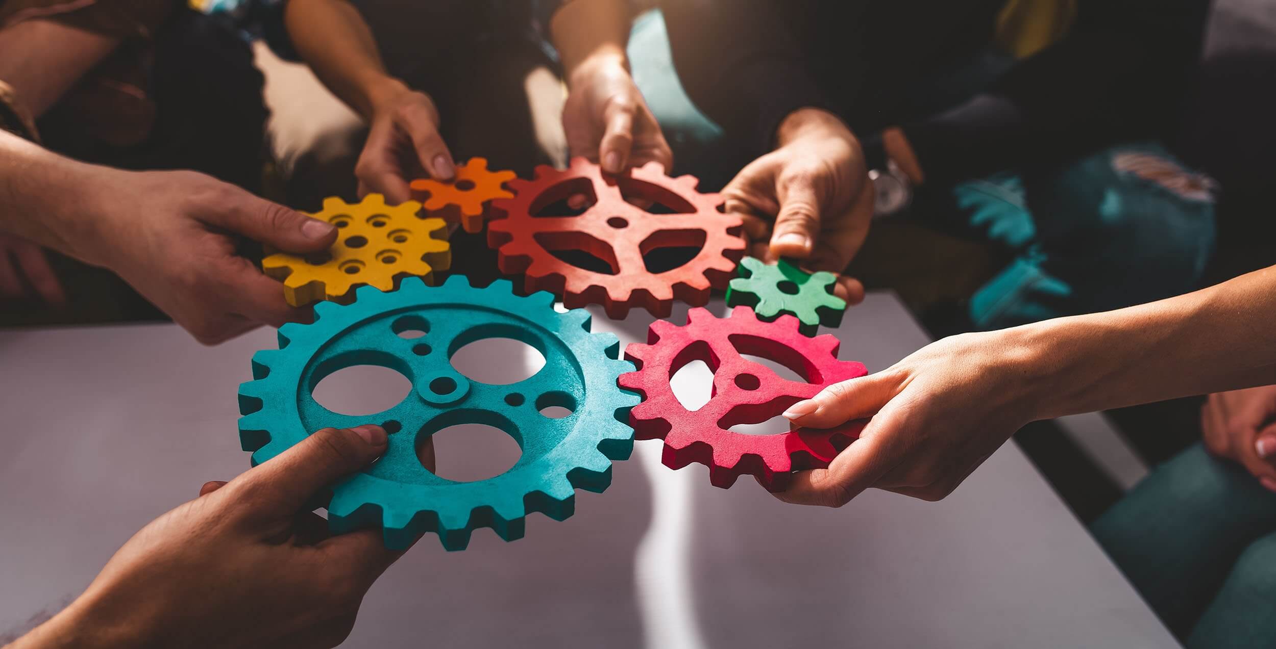 Teamwork och samarbete – händer som sammanfogar kugghjul symboliserar SVEFABs helhetslösning inom fastighetsförvaltning