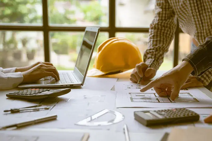 Byggritningar och skyddshjälm på arbetsbord – projekt och entreprenader för fastigheter