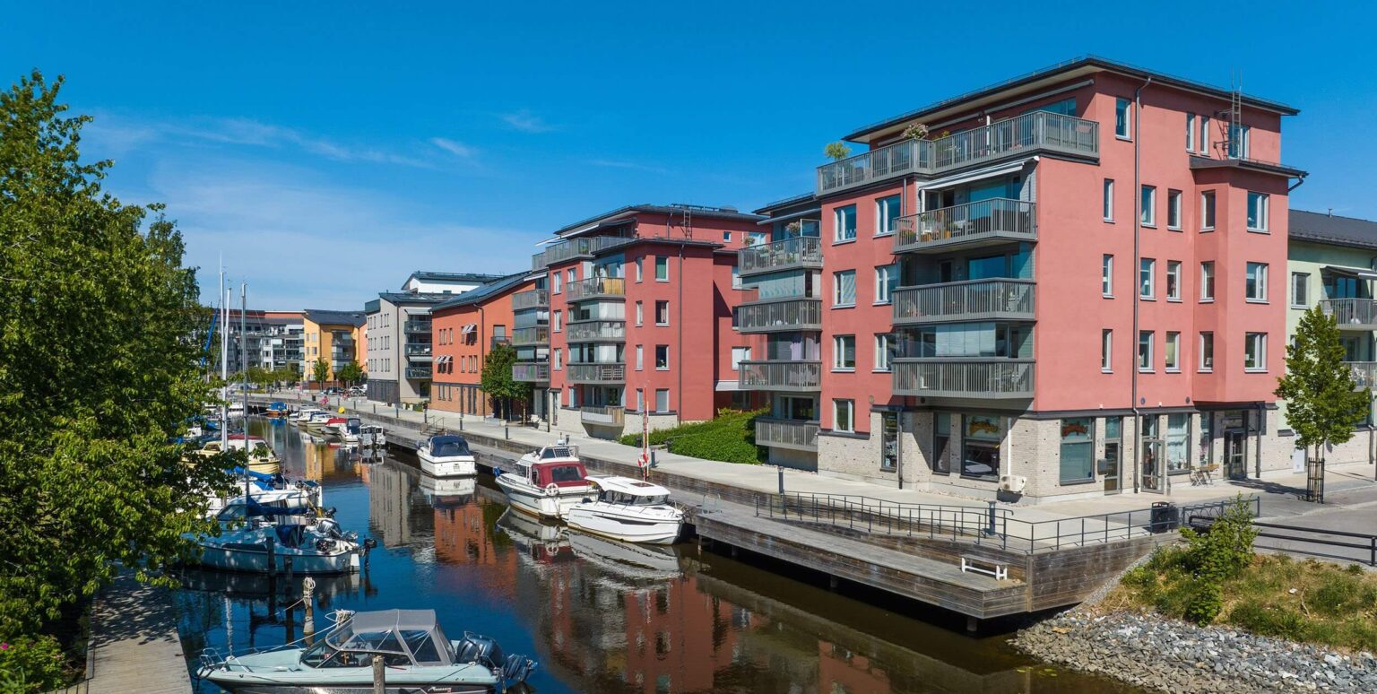 Moderna, röda, flerbostadshus (BRF) vid kanal i Stockholmsområdet – Teknisk fastighetsförvaltning Stockholm för BRF och fastighetsägare.