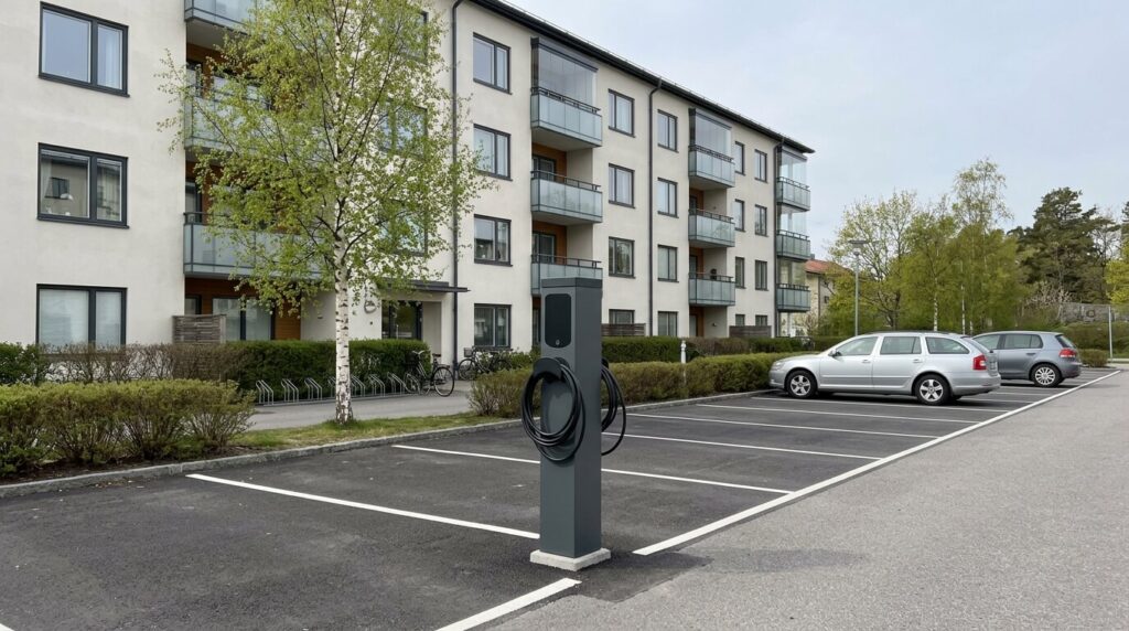 Laddstolpe för elbil vid parkeringsplatser utanför flerbostadshus i Stockholm en vårdag